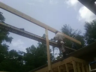 Carpenter setting a ridge beam over a new addition frame — Ice Dam Removal by Roofing Brothers in Harper