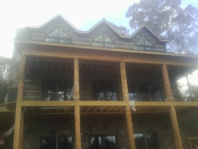 Dormers and porch framing on a large log home under construction — Roof Coating work by our crew in Harper