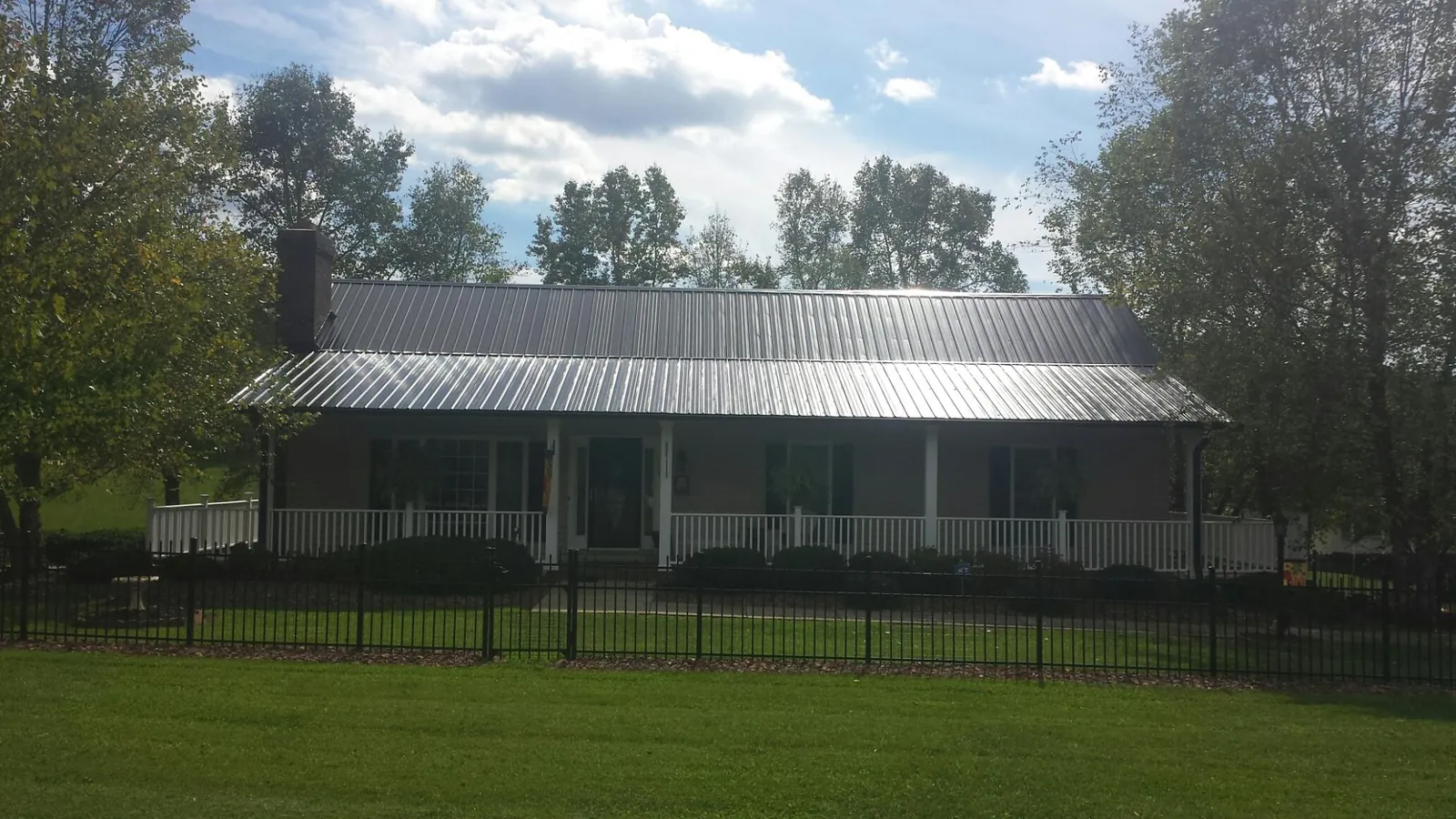 Gray metal roof on a brick ranch with a full width front porch — Gutter Guard Installation work by our crew in Harper