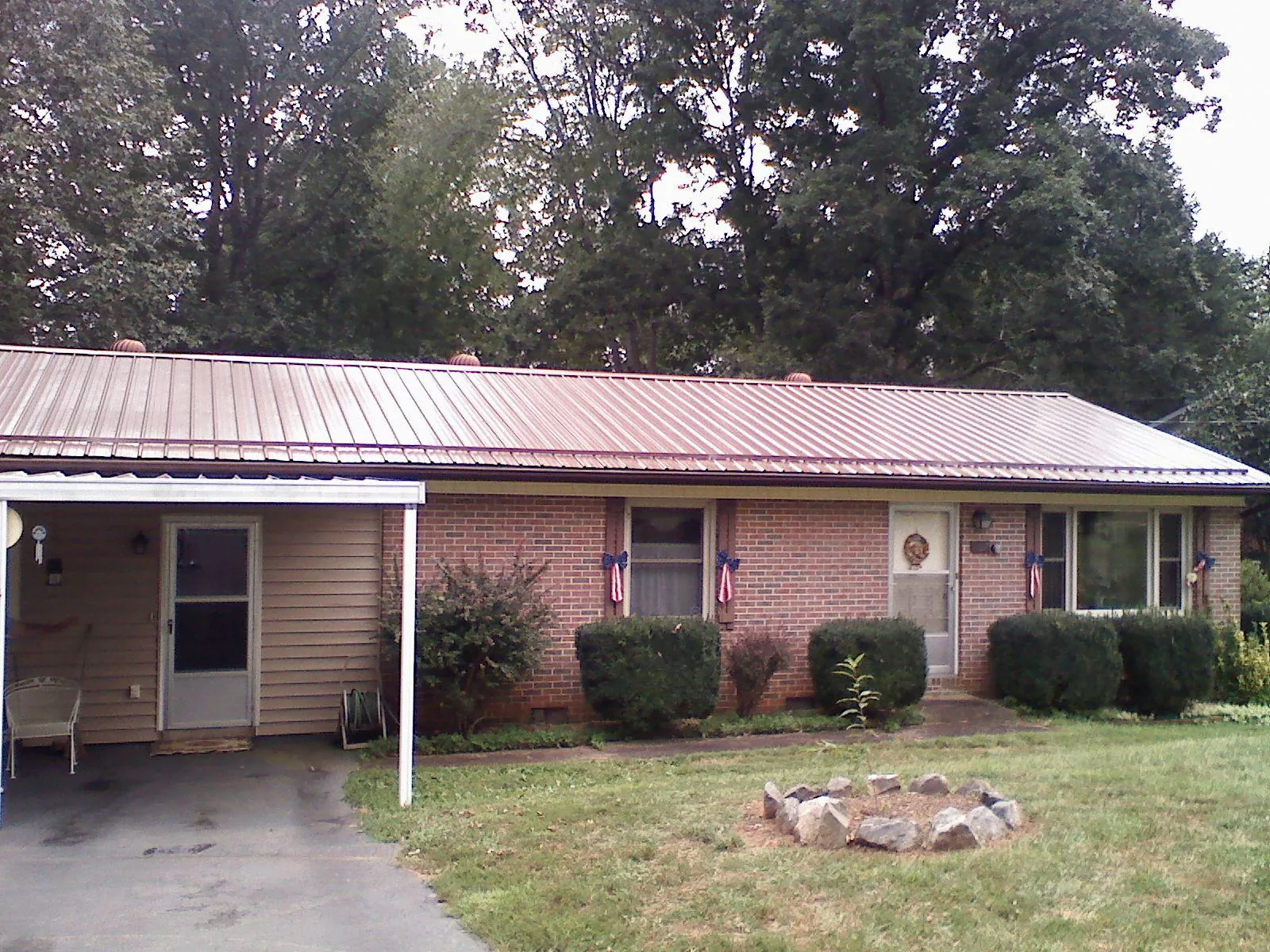 Bronze metal roof and carport on a brick ranch home — Roof Repair work by our crew in Harper