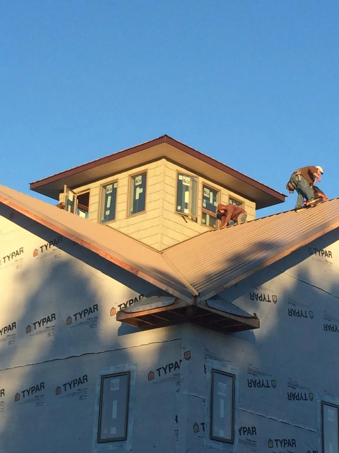 Roofers working around a rooftop cupola on a new metal roof at sunset — Roof Waterproofing in Harper by Roofing Brothers